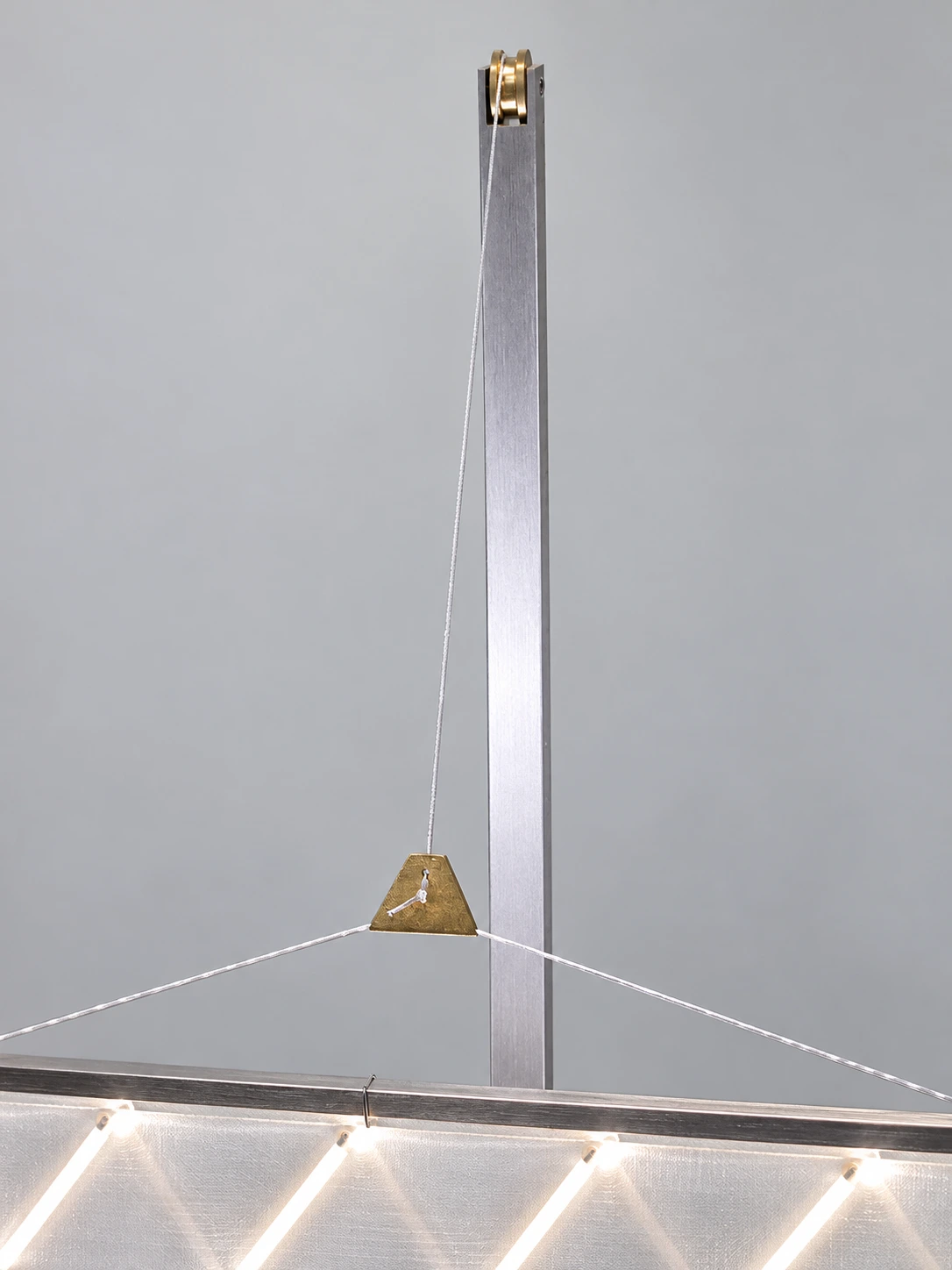 Close view of the pulley, cord and three-point bridle that lower the LED sail from the aluminium mast